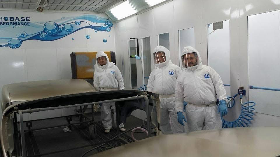 Jimmy's Auto Repair and Body Shop paint team standing in protective suits inside the paint booth